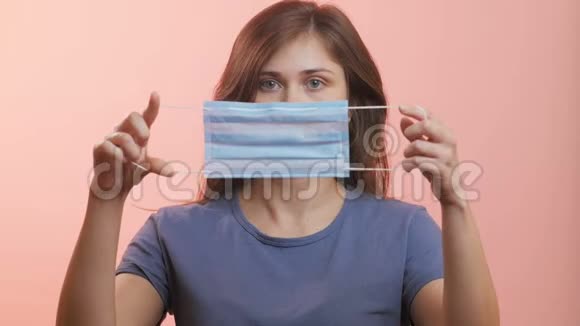 一位年轻女性在摄影棚背景下戴着医用防护面罩白种人女孩防止病毒流行病和疾病的传播视频的预览图