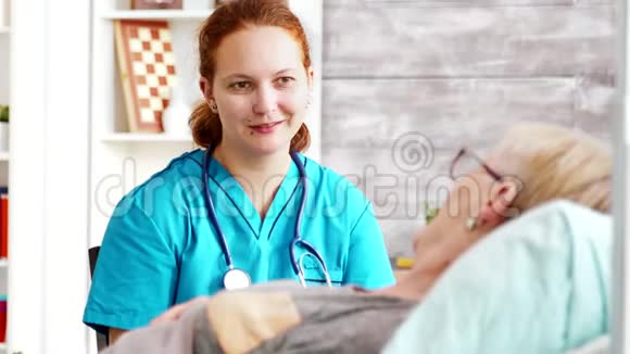 一张女助手与躺在病床上的老太太谈话的照片视频的预览图