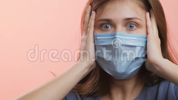 一位戴着医用防护面罩的年轻女子的脸在演播室的背景上深深地呼吸着女孩用惊恐的眼睛看着害怕视频的预览图