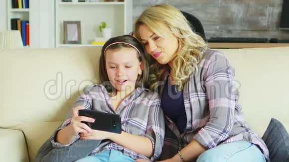 年轻的母亲和女儿在沙发上放松视频的预览图