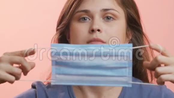 一位年轻女性的头戴着面具在工作室背景下脸上和嘴上戴着面具对潘迪米的保护方法的概念视频的预览图