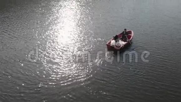 空中拍摄的新娘在红船里游泳明亮的阳光反射在湖面上形成倒影闪烁视频的预览图