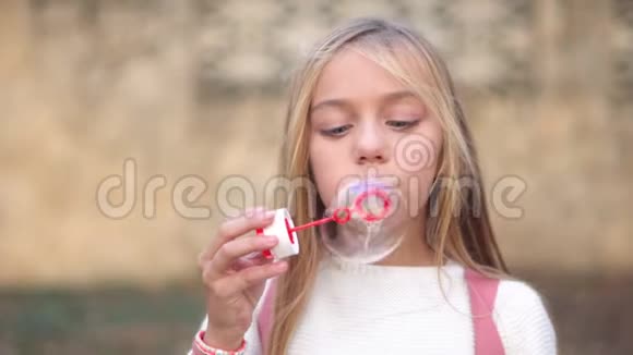快乐的小女孩在户外玩耍吹肥皂泡在公园里玩得很开心视频的预览图