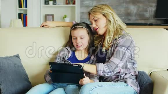 美丽的年轻母亲用平板电脑教育女儿视频的预览图