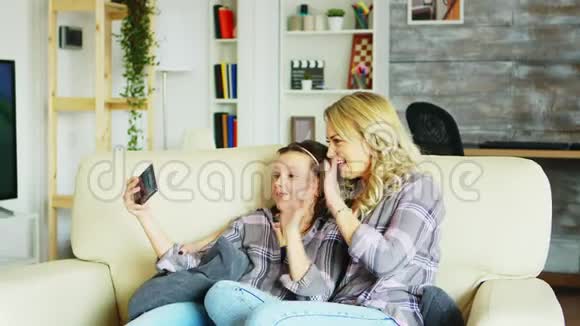 小女孩和她妈妈坐在客厅的沙发上视频的预览图