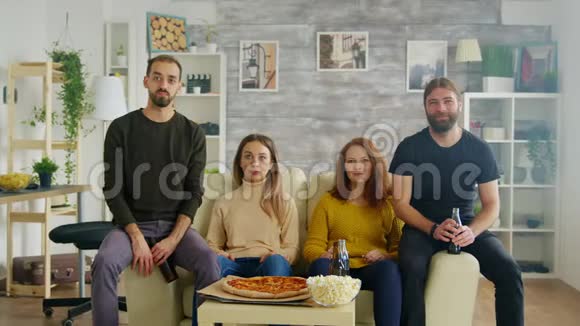 一群朋友坐在沙发上伸手要披萨视频的预览图