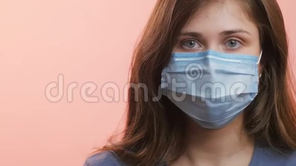 一位年轻女性的头部在工作室背景下戴着医用防护面罩女孩防止病毒传播并表现出良好的姿态epi视频的预览图