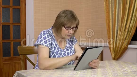 一个女人第一次使用平板电脑一位老妇人正在使用平板电脑一个舒适的房间里的女人视频的预览图