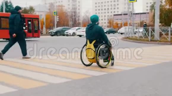 坐轮椅的残疾人穿过城市的道路视频的预览图