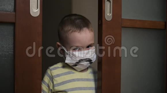 悲伤的男孩戴着医疗面具看着镜头失望病毒防护大流行预防流行视频的预览图