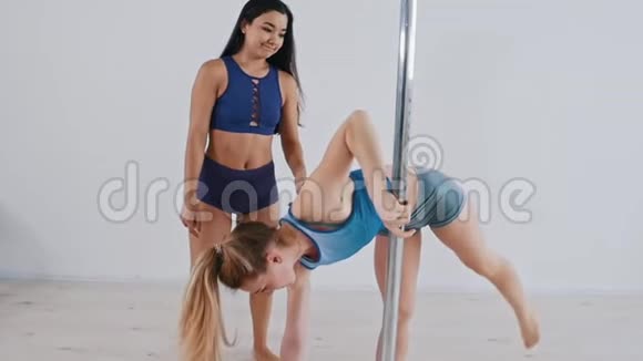 一位年轻女子倒立着举着一根杆子她的教练帮她站在这个位置上视频的预览图