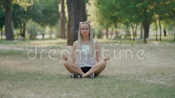 夏日夕阳下年轻女子在公园里冥想视频的预览图