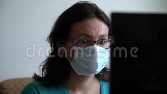 女人戴上面具在笔记本电脑上读到关于病毒泛滥的新消息看上去吓坏了感到震惊和沮丧视频的预览图