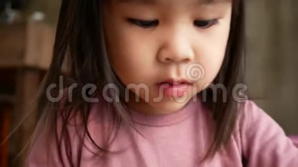 亚洲小女孩在家里玩着在塑料杯里吃面条垃圾食品概念视频的预览图