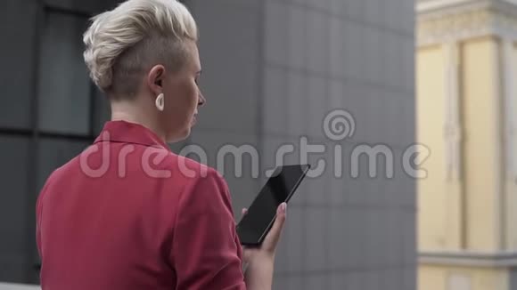 镜头跟随一位年轻时尚的金发女人手里拿着手机视频的预览图