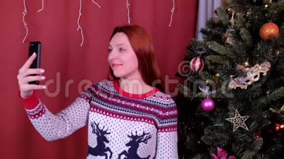 年轻女子在装饰圣诞树附近拍照节日圣诞节和新年的概念视频的预览图