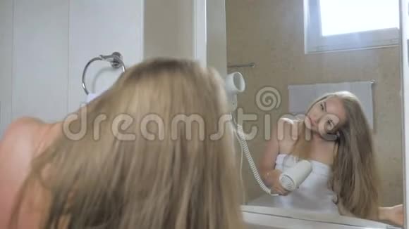 穿着浴巾的漂亮少女正在浴室里用吹风机照镜子视频的预览图