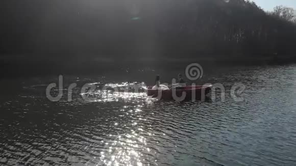 空中拍摄的新娘在一艘红色的船上游泳明亮的阳光反射在湖面上形成倒影闪烁视频的预览图