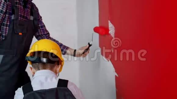 一个带着父亲在透明的公寓里画红色墙壁的小男孩视频的预览图