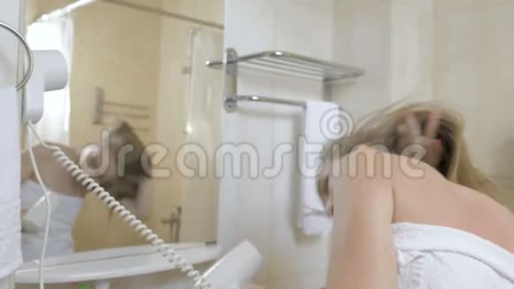 穿着毛巾在浴室里晒头发的有趣女孩视频的预览图