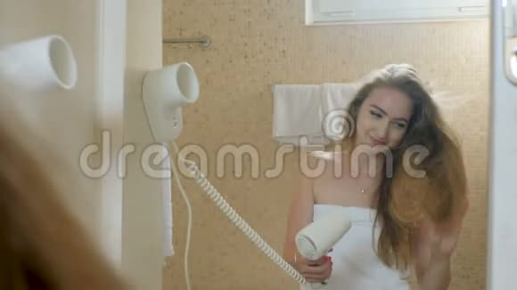 穿着毛巾在浴室里晒头发的有趣女孩视频的预览图