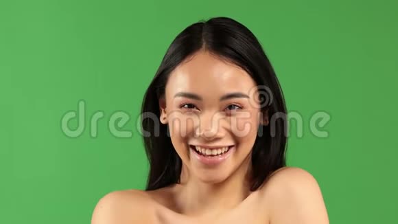 美丽的年轻亚洲女人微笑着看着绿背景上的摄像机视频的预览图