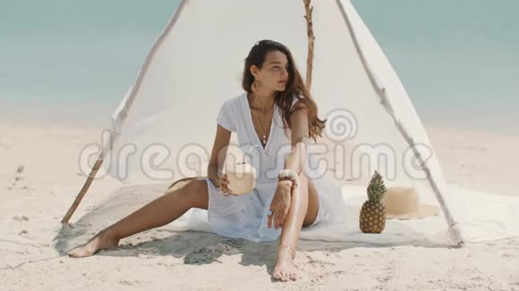 女人一边喝椰子汁一边在海滩上放松视频的预览图