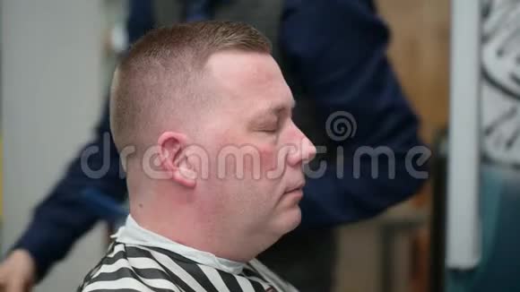 男人理发店理发主人用剪刀和梳子剪人的眉毛视频的预览图