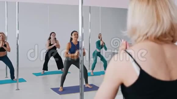 年轻女性在跳舞前在镜子前热身身体蹲下视频的预览图