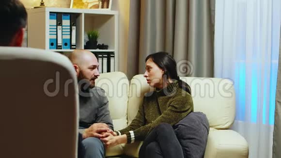 伤心的女友牵着丈夫的手坐在沙发上视频的预览图