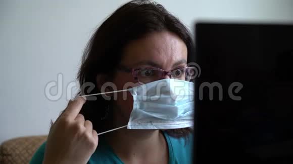 戴着面具和眼镜的女人在笔记本电脑上读到关于病毒流行的新消息看上去吓坏了又沮丧视频的预览图