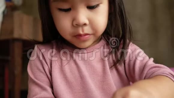 亚洲小女孩在家里玩着在塑料杯里吃面条垃圾食品概念视频的预览图
