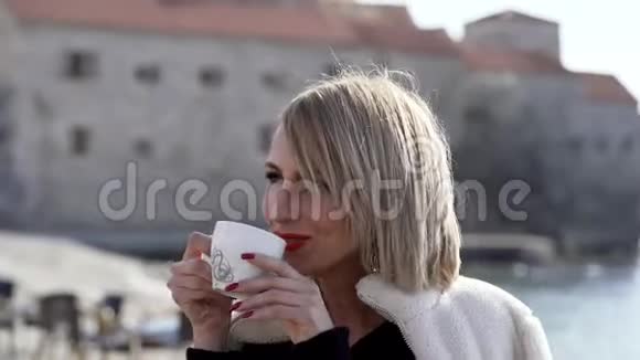 美丽的女孩在海滩上喝早咖啡视频的预览图