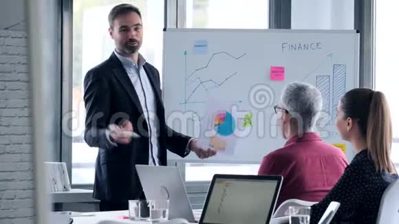 英俊的商人用白板向同事解释一个项目视频的预览图