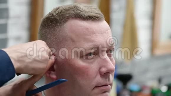 理发店的男式理发一位剪头发金发的男士的贴身剪裁视频的预览图