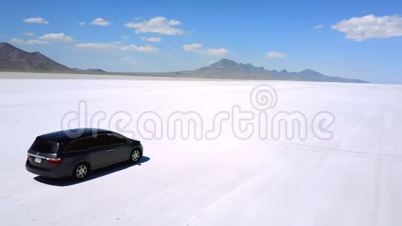无人机照相机跟随银色小型货车行驶在平坦的盐湖沙漠令人叹为观止的景色中驶向远山视频的预览图