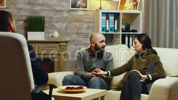 年轻夫妇手牵手坐在沙发上视频的预览图