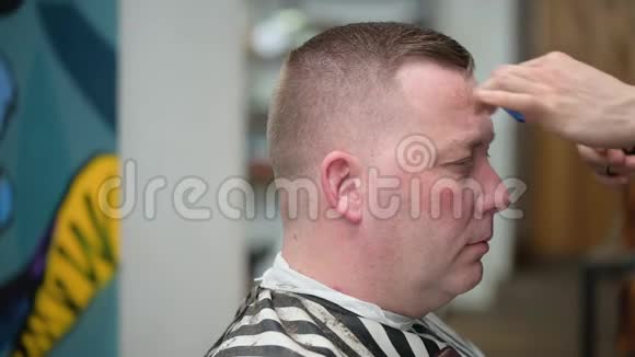 男人理发店理发主人用剪刀剪一个人头发视频的预览图