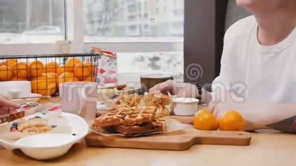 一对可爱的夫妇在咖啡馆吃午餐吃华夫饼和煎饼牵着手视频的预览图