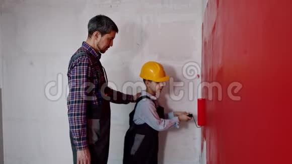 公寓翻新父子在新公寓用红色油漆覆盖墙壁视频的预览图