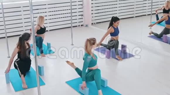 年轻女性在明亮的瑜伽垫上做健身运动手拿砖头视频的预览图