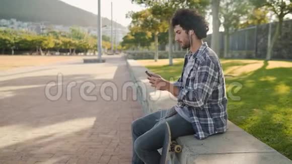 一个年轻人在公园里的人行道上玩滑板打了手机视频的预览图