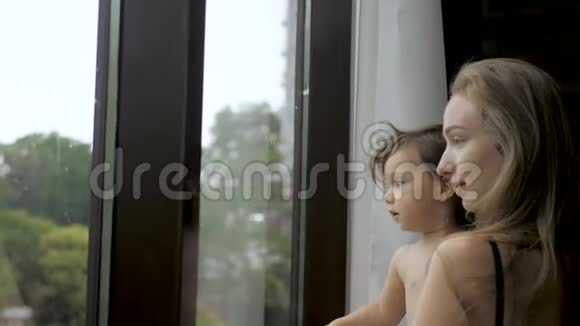 幼儿女孩和妈妈站在全景窗的背景上视频的预览图