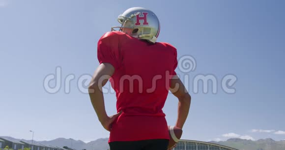 美国足球运动员戴着头盔和橄榄球视频的预览图
