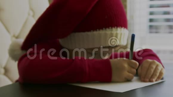 一个穿着红色毛衣的小男孩坐在桌子旁手里拿着一支钢笔在空白的白色上写字或画画视频的预览图