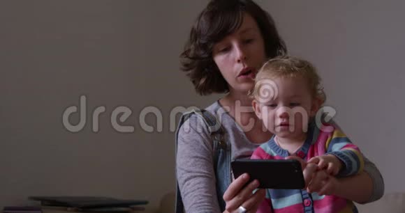 带着婴儿看智能手机的白人女性视频的预览图