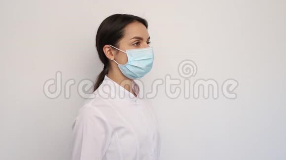 戴着白色医疗手套和防护面罩的女医生在他的脖子上放了一个听诊器人和医学概念视频的预览图