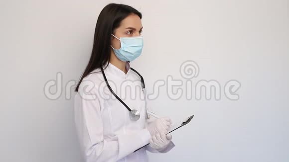 友好的女医生穿着白色的医用外套手套和防护面罩把诊断写在客户卡上视频的预览图