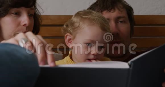 夫妇在家给宝宝看书的正面景色视频的预览图