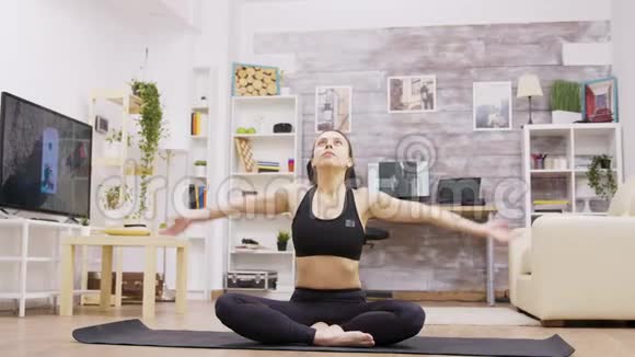 在客厅做瑜伽冥想的年轻女性视频的预览图